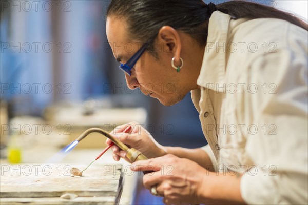 Close up of Native American jeweler using blowtorch in studio