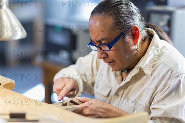 Close up of Native American jeweler working in studio
