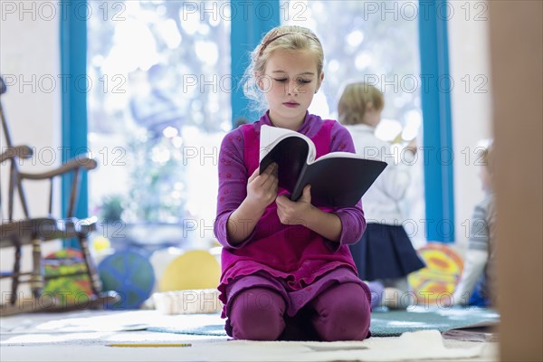 Caucasian girl reading book on floor