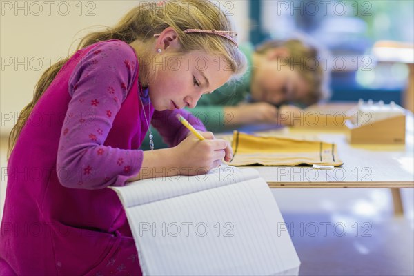 Caucasian girl writing in classroom