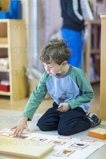 Boy arranging cards on floor in classroom