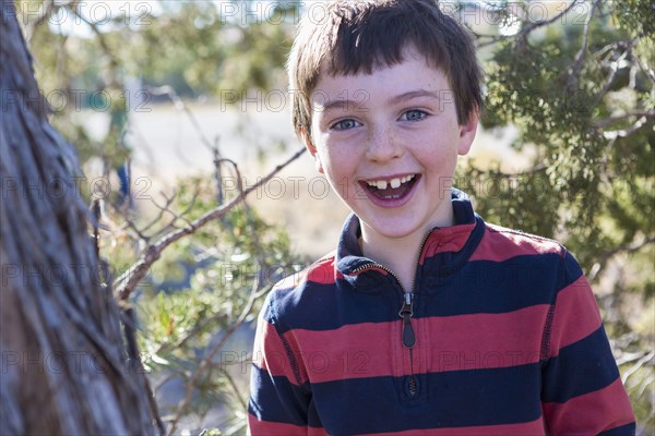 Close up of Caucasian boy smiling near tree