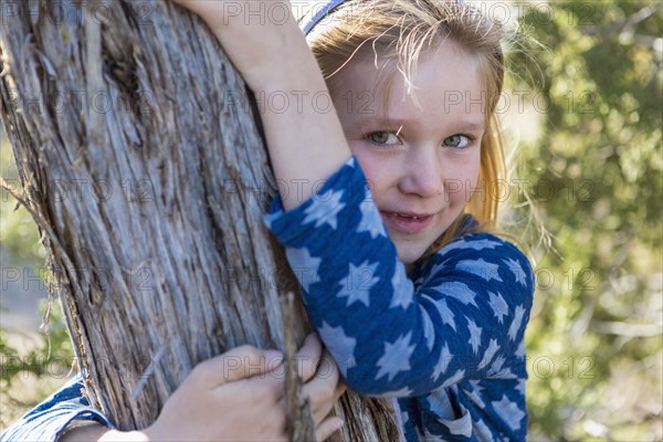 Caucasian girl hugging tree outdoors