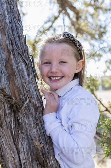 Mixed race girl smiling near tree outdoors