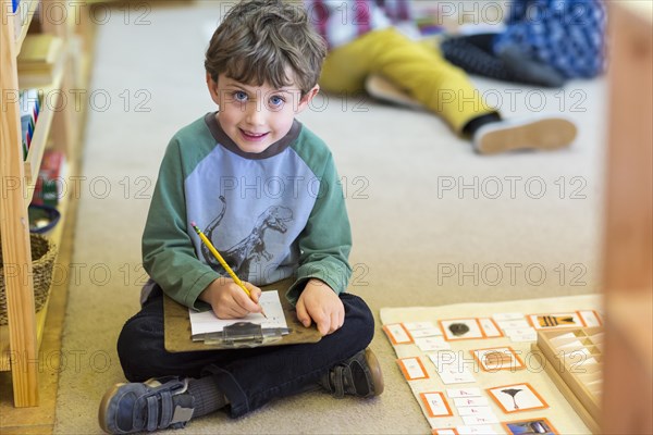 Smiling boy writing in classroom