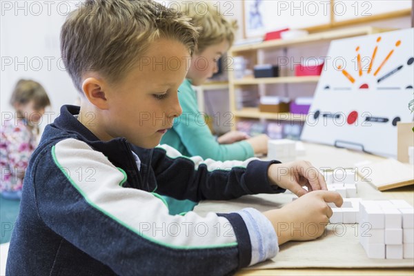 Close up of boy solving puzzle in classroom