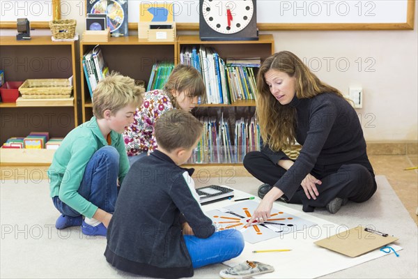 Montessori teacher helping students in classroom