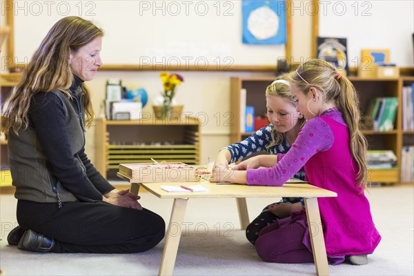 Montessori teacher helping students in classroom