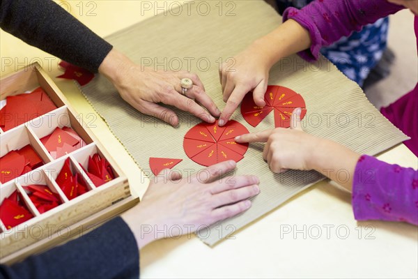 Close up of Caucasian Montessori teacher and student solving puzzle