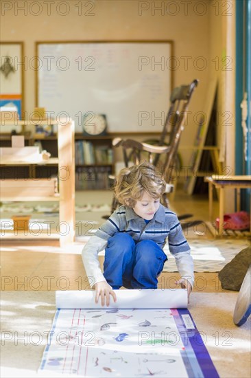 Boy rolling up poster in classroom