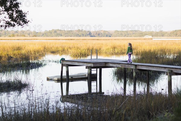 Caucasian girl walking on wooden dock in lake