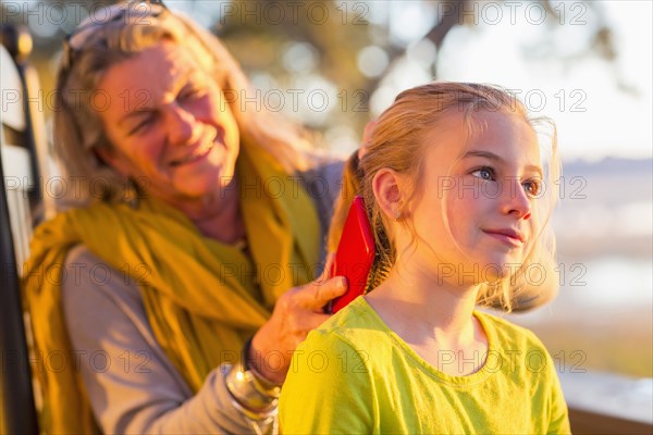 Caucasian grandmother brushing hair of granddaughter