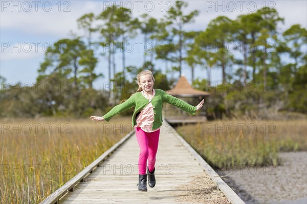 Caucasian girl running on wooden walkway