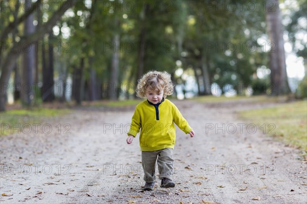 Caucasian baby boy walking on dirt road