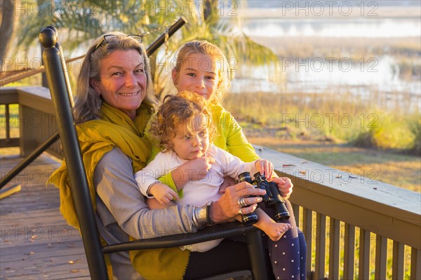 Caucasian grandmother and grandchildren using binoculars on porch