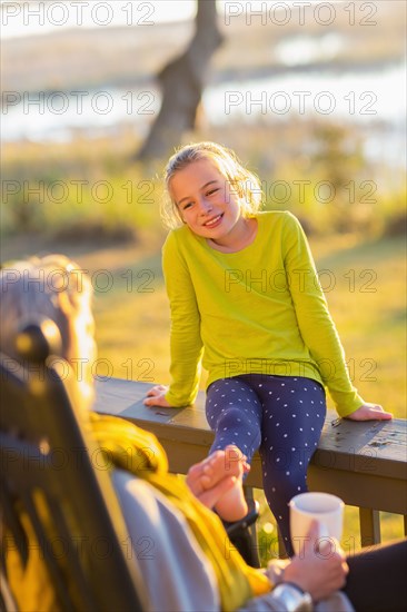 Caucasian grandmother and granddaughter relaxing on porch