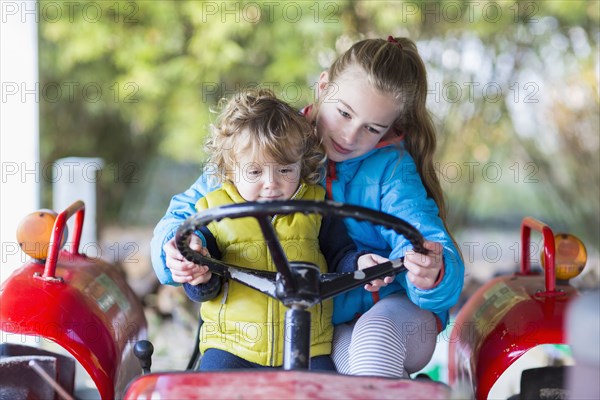 Caucasian brother and sister driving tractor