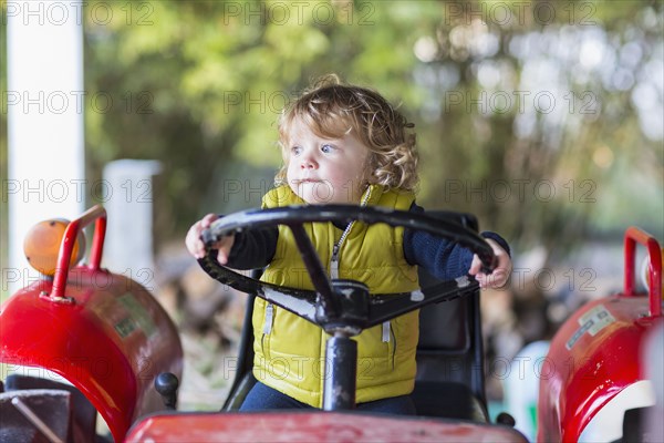 Caucasian baby boy driving tractor