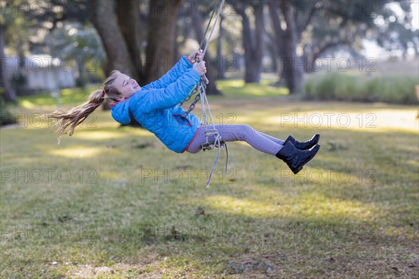 Caucasian girl playing on swing