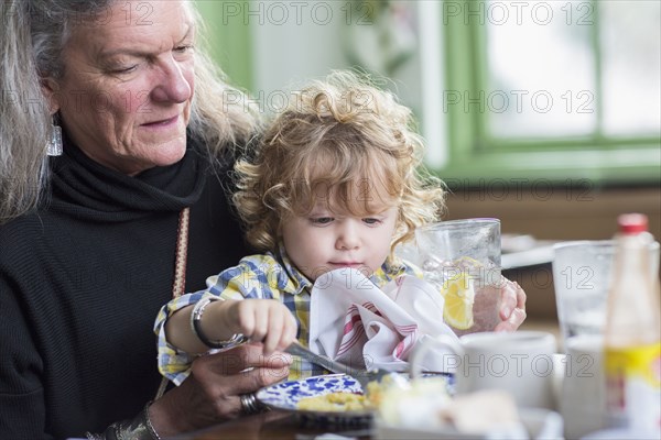 Caucasian grandmother and grandson eating dinner in restaurant