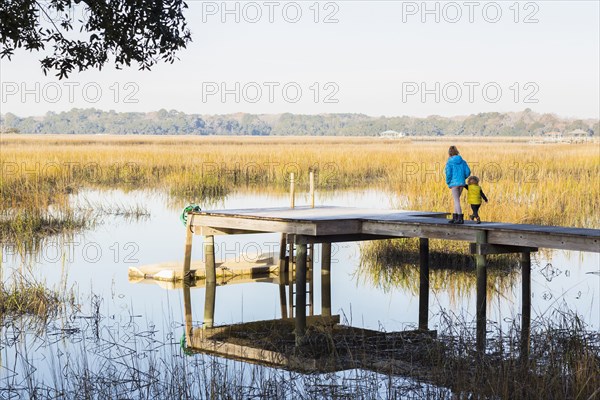 Caucasian children walking on wooden dock over lake
