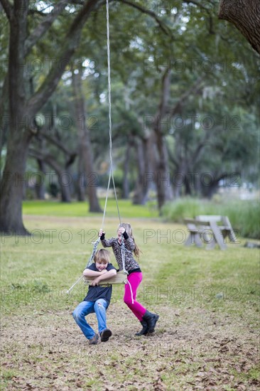 Caucasian children playing on swing in park