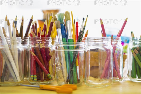 Close up of jars of colored pencils and paintbrushes