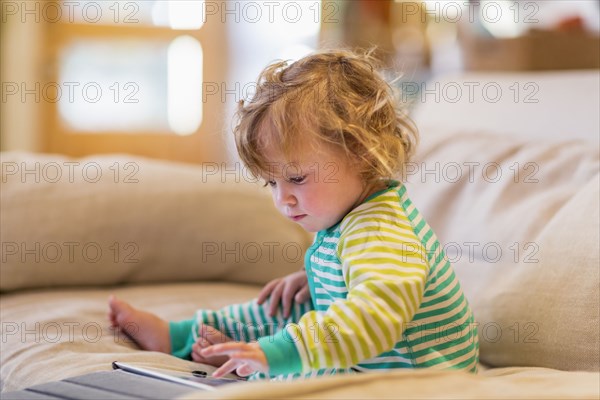 Caucasian baby boy using digital tablet on sofa