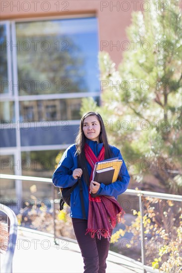 Mixed race student holding books on campus