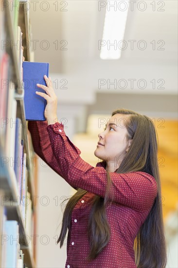 Mixed race student selecting book in library