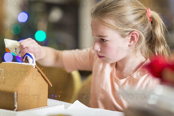 Caucasian girl decorating gingerbread house