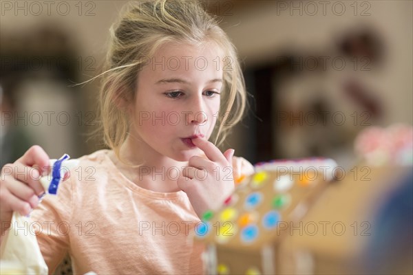 Caucasian girl decorating gingerbread house