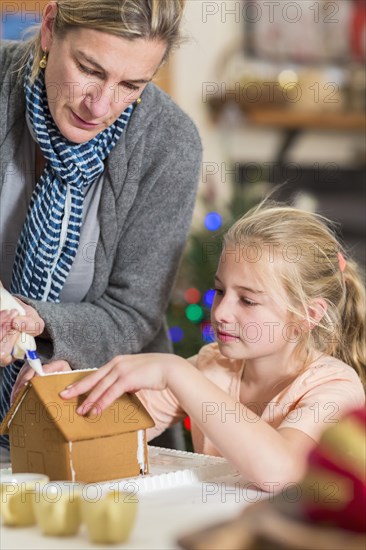 Caucasian mother and daughter decorating gingerbread house