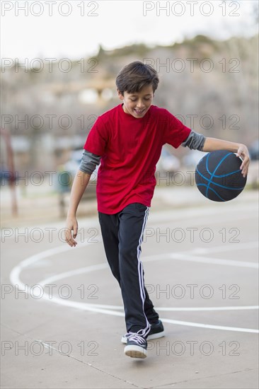 Caucasian boy playing basketball on court