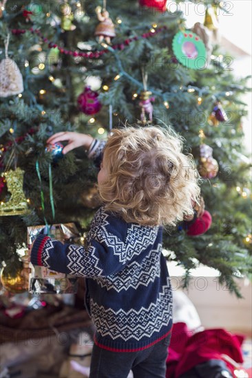 Caucasian baby boy decorating Christmas tree