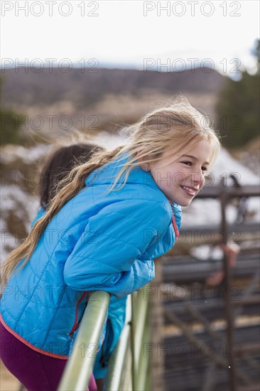 Caucasian girl standing on fence on farm