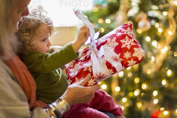 Caucasian grandmother and grandson opening presents near Christmas tree