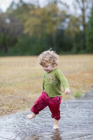 Caucasian baby boy splashing in puddle