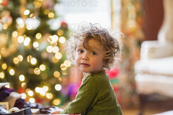 Caucasian baby boy sitting near Christmas tree