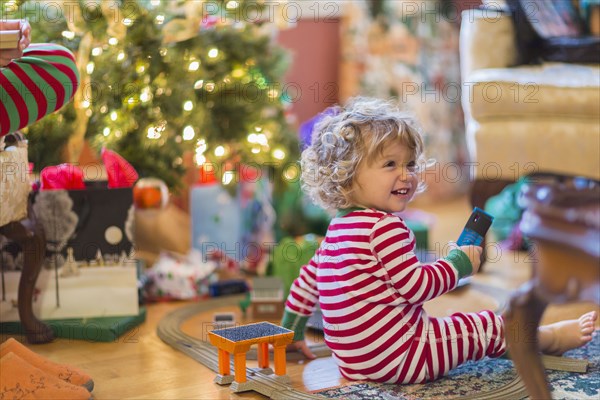 Caucasian baby boy opening presents near Christmas tree