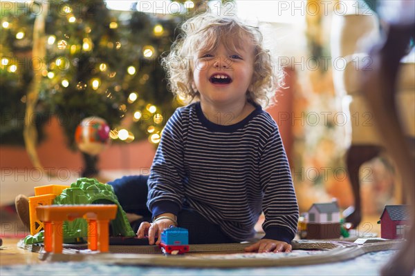 Caucasian baby boy playing with toys near Christmas tree