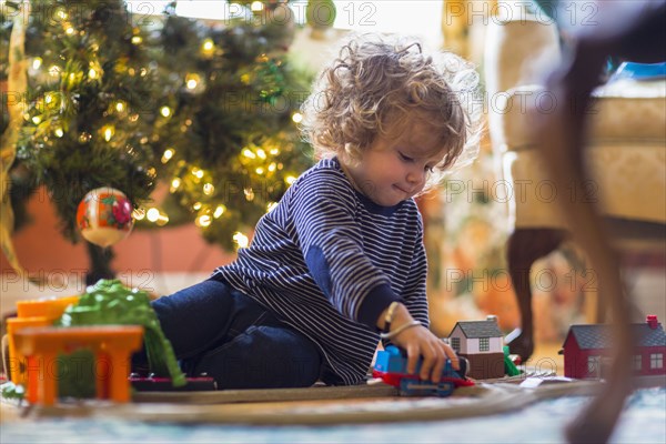 Caucasian baby boy playing with toys near Christmas tree