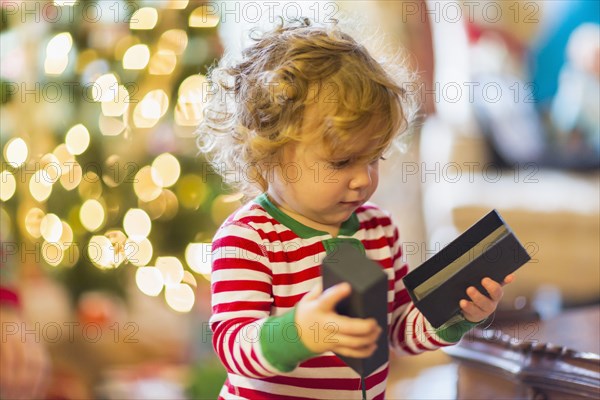 Caucasian baby boy opening present near Christmas tree