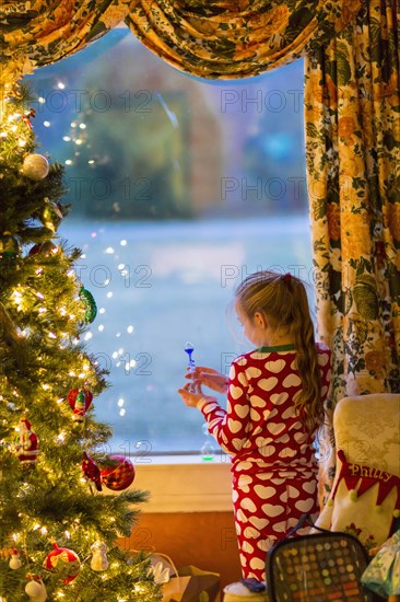 Caucasian girl opening present near Christmas tree