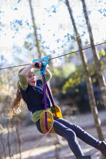 Caucasian girl zip lining in forest