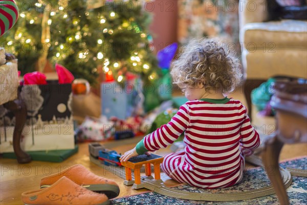 Caucasian baby boy playing with toys near Christmas tree