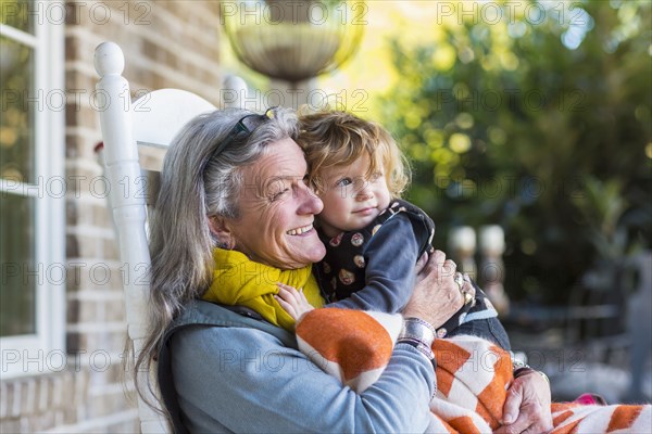 Caucasian grandmother and grandson sitting on porch