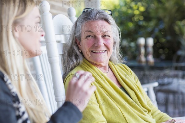 Caucasian mother and daughter talking on porch