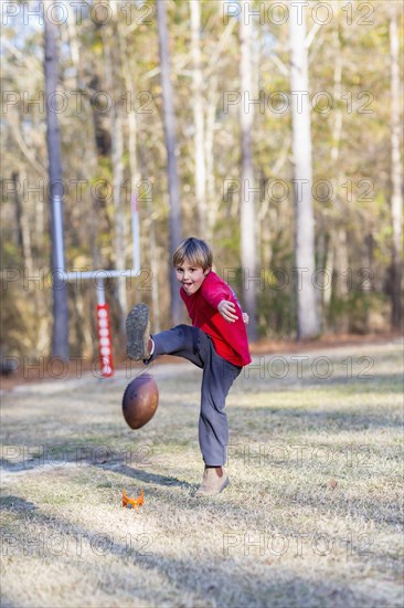 Caucasian boy kicking football in field