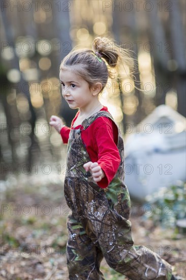 Caucasian girl wearing camouflage overalls outdoors